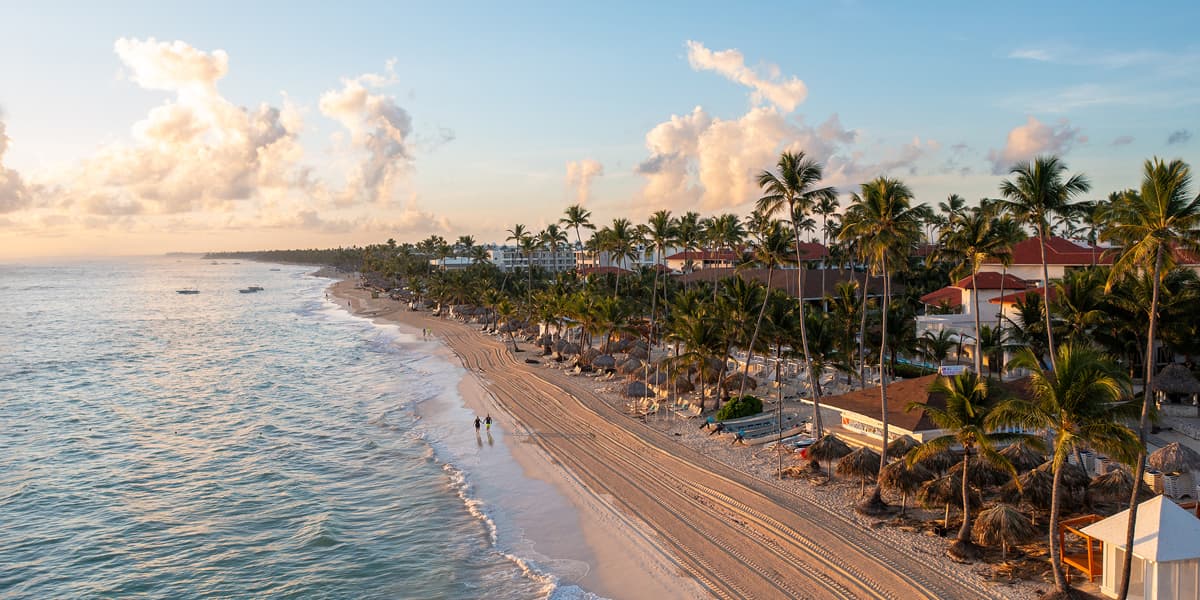 Punta Cana, Dominican Republic, at sunset, with palm-lined beach, calm water, and a serene luxury coastal view.
