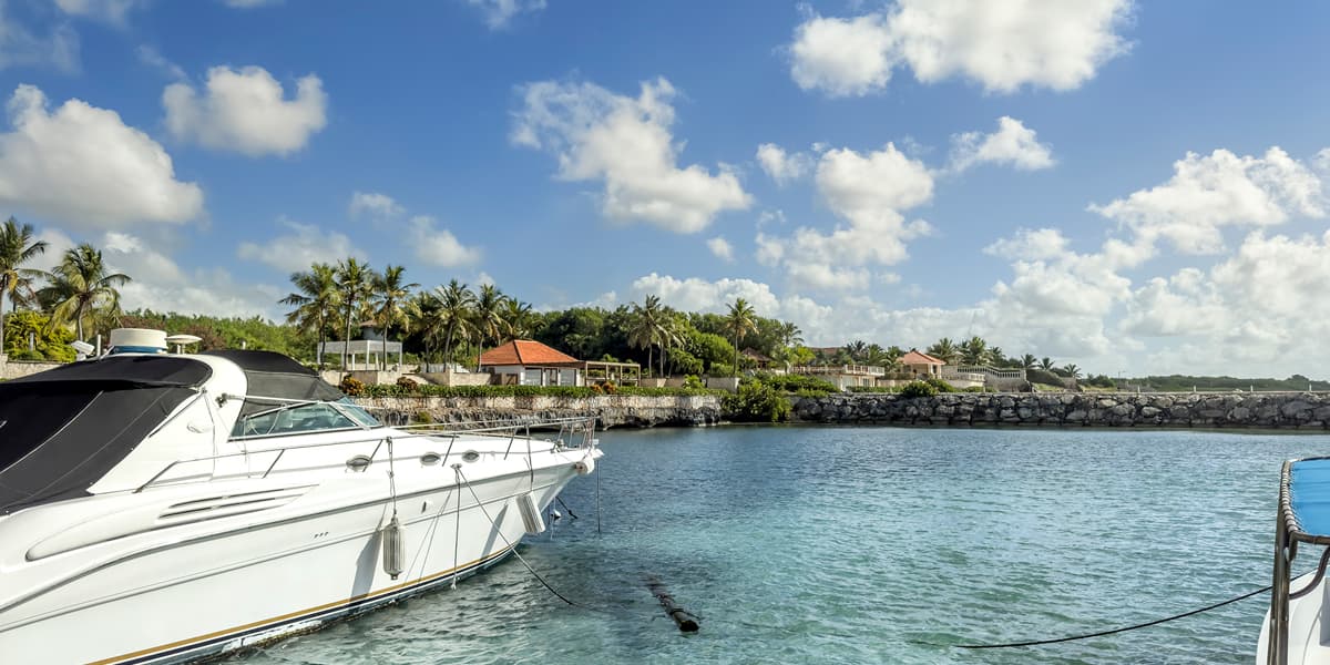 Luxury yacht in the Dominican Republic, with calm water, palm-lined shore, and a bright tropical sky.